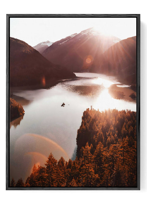 Aerial view of a serene lake surrounded by evergreen trees at sunset.