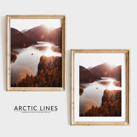 Atmospheric mountain landscape with sunburst effect and calm water.