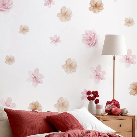 Bedroom with floral wall decals, red pillows, and a lamp.