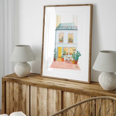 French watercolor print with pastel building and red patterned rug


