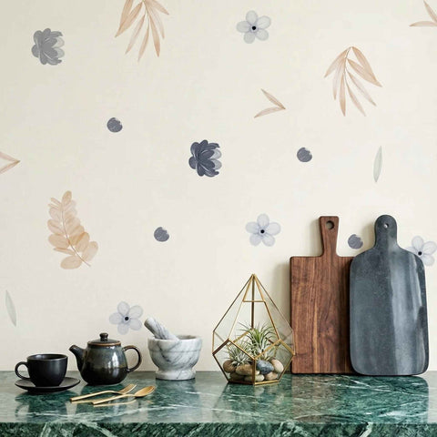 Decorative wall with floral decals, cutting boards, and kitchen items on a marble countertop.