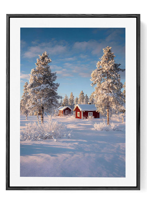 Sunlit snow landscape photography with red Swedish cabins and blue sky