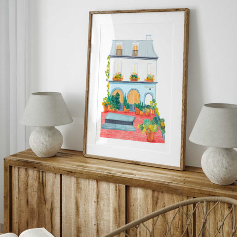 Townhouse watercolor print with red patio and leafy potted plants

